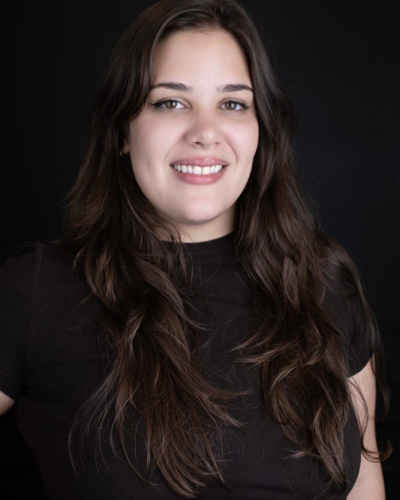 Irene Martin, smiling, in a black top against a dark background